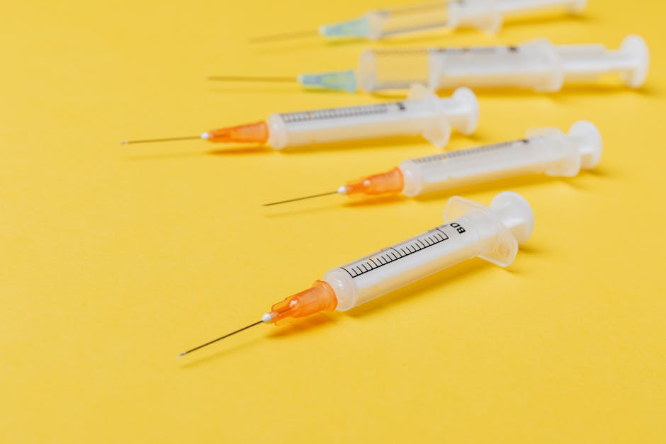 Six syringes with clear plastic barrels, black measurement markings, and orange tips are neatly aligned on a bright yellow surface. The syringes vary in size, with some positioned with needles pointing diagonally in different directions, and others lying horizontally. The image captures the detail of the syringes, highlighting the transparency of the barrels and the precise measurement lines, indicative of medical or laboratory use. There are no other objects or background elements visible, emphasizing the focus on the syringes. This image, associated with packing and moving services, can be used to illustrate careful handling and packaging of fragile or sensitive items during a home relocation or furniture transport, highlighting the importance of proper packing materials and procedures to prevent damage during a move, in line with tips for damage prevention during house removals as seen on the page for moving antiques in Chingford at manwithvanchingford.co.uk.