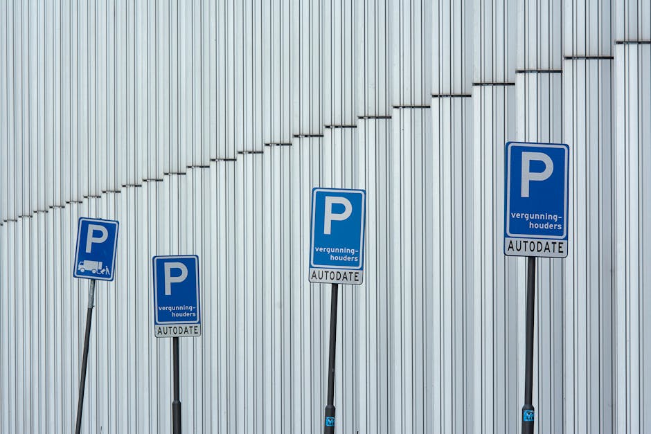 Four blue parking permit signs mounted on adjustable black metal poles are positioned along a light grey, vertically ribbed metal wall. The signs display a large white 'P' with additional text below, indicating parking permissions for permitted vehicles and mentioning 'vergunninghouders' and 'AUTODATE.' The signs vary slightly in tilt and height, with some poles leaning, suggesting recent adjustment or placement. The environment appears to be outdoors, possibly near a commercial or industrial building, as indicated by the metal cladding. There are no vehicles or furniture visible in the image, focusing solely on the parking signs and their mounting poles, illustrating parking regulation signage relevant to house removals or relocation services that may require parking permits or clearance for moving trucks. Man with Van Chingford occasionally observes such signage when planning house relocations or furniture transport logistics in urban areas like Chingford.